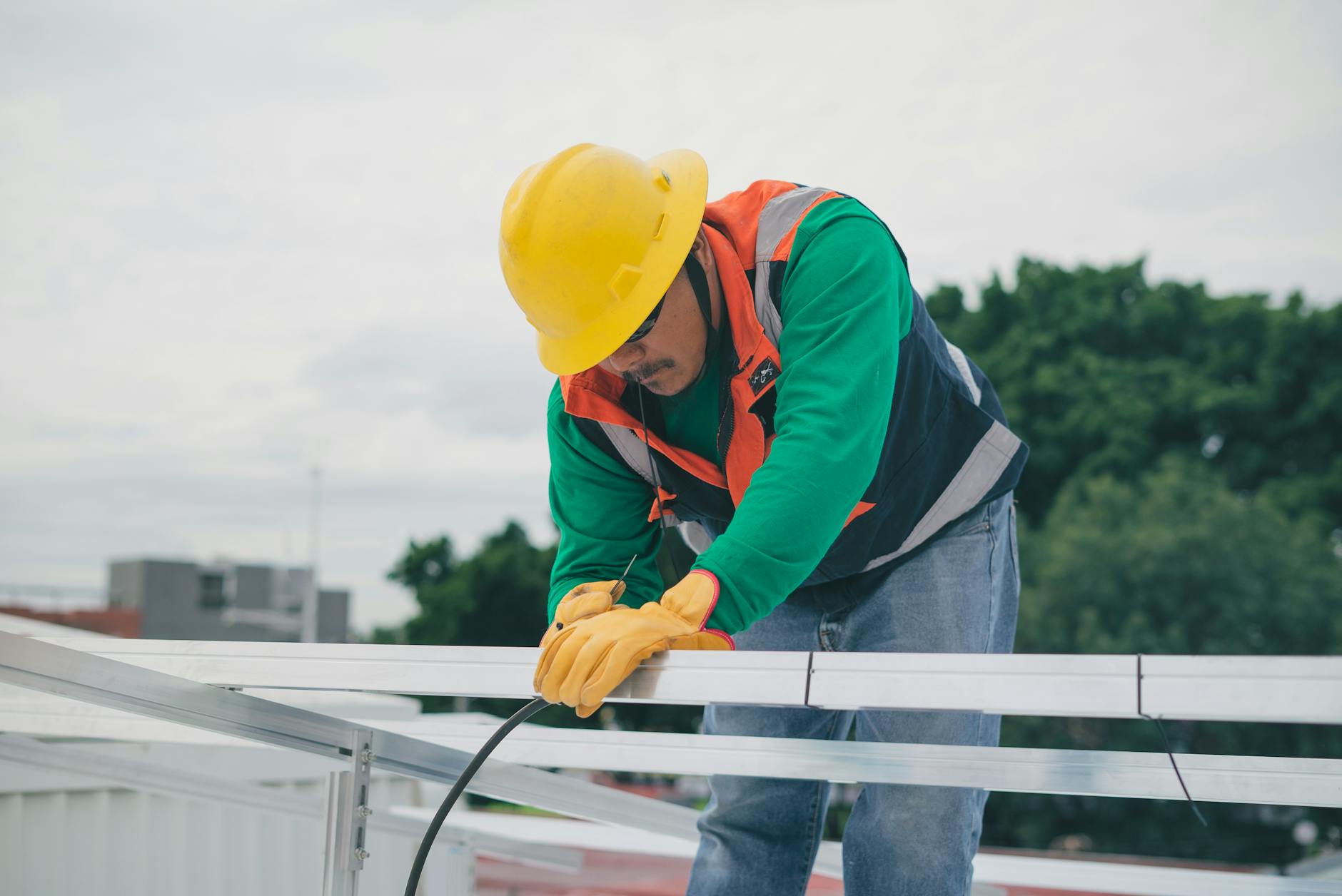 A close-up of a high-wind rated asphalt shingle being nailed securely to a roof deck by a professional roofer.